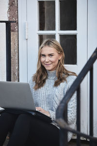 Woman using laptop on front stoop
