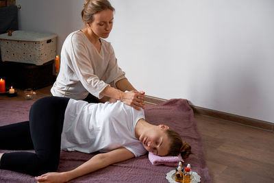 Woman massaging customer lying on floor in spa