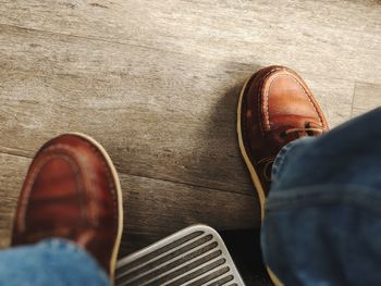Low section of person wearing shoes on wooden floor