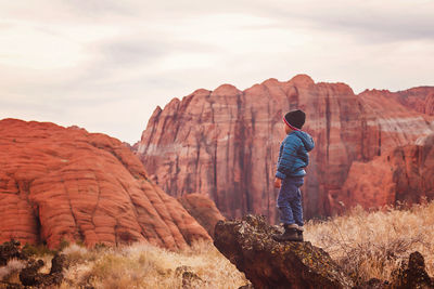 Little boy by the red sandstone cliffs and mountains in utah