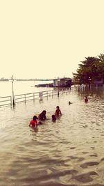 People swimming in sea against clear sky