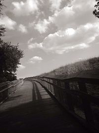 Road passing through trees against cloudy sky