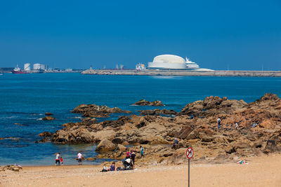 People on beach against clear blue sky