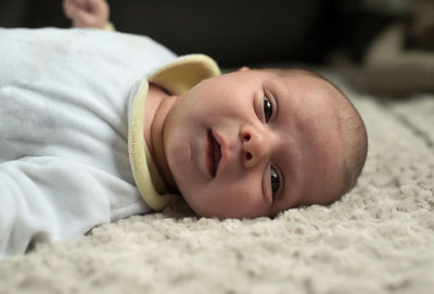 Close-up portrait of cute boy lying on bed