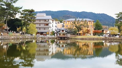 Buildings by lake against sky in city