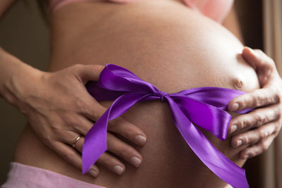 Close-up of woman tied up on purple hand