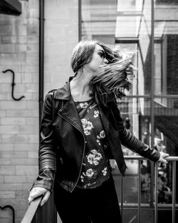 Young woman wearing jacket standing in balcony