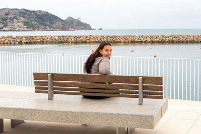 Young girl looking back, seated on seaport lookout point