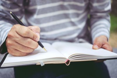 Close-up of man writing in book