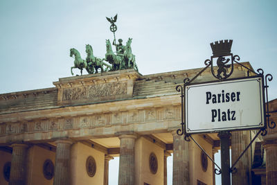 Low angle view of sign board by brandenburg gate against clear sky