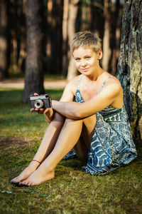 Portrait of woman photographing while sitting in forest