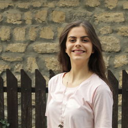 Portrait of smiling woman standing against wall