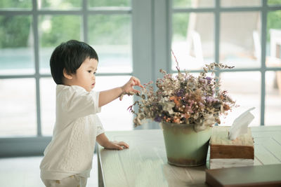 Girl holding flower pot on table