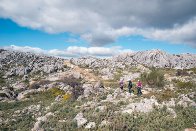 Concept: adventure. three climbers with helmet and harness. walking on the plain at the top of the mountain. limestone rock landscape and low vegetation. andalusia, spain.