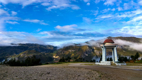 Built structure on landscape against cloudy sky