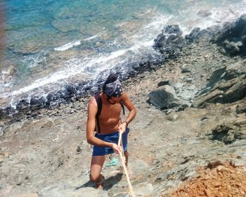 Full length of shirtless man holding rock