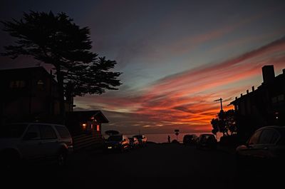 Silhouette cars on street against sky during sunset