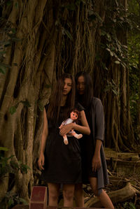 Portrait of woman sitting against tree