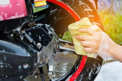 Cropped hand washing motorcycle wheel