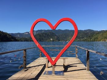 Heart shape on pier against lake against clear blue sky bled castle fortress 