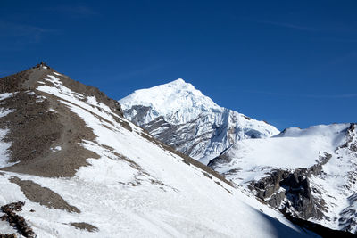 Scenic view of snowcapped mountains against blue sky