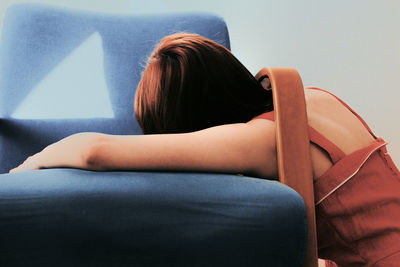 Rear view of woman leaning on sofa