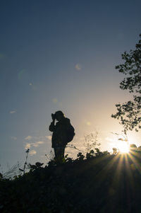 Silhouette man standing by tree against sky during sunset