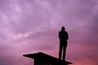 Low angle view of silhouette man standing against sky during sunset