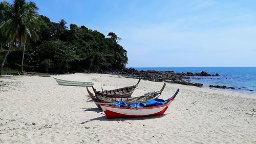 Deck chairs on beach against sky