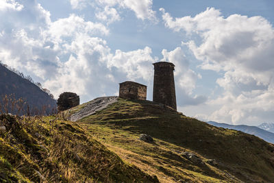 Scenic view of built structure on field against mountains and sky