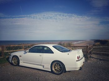 Car on road by sea against sky