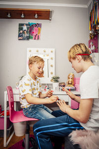 Boy applying nail polish on brother in room