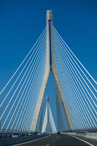 Low angle view of suspension bridge against blue sky