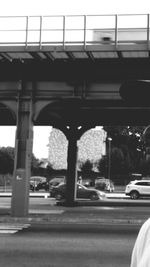 Vehicles on road against bridge in city