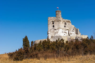 Low angle view of old building against clear blue sky