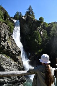 Little girl from behind admiring an alpine waterfall, lillaz, aosta, italy