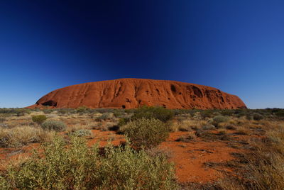 Rock formations on landscape against clear blue sky