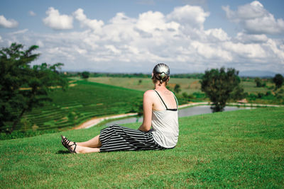 Rear view of woman sitting on field