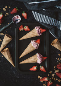 Top view of strawberry ice cream cones on a black background.