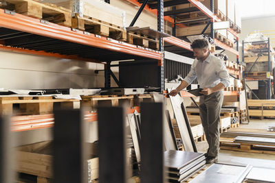 Businessman with digital tablet inspecting material while standing at factory