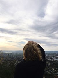 Rear view of woman looking at cityscape against sky