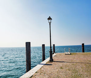 Wooden post in sea against clear sky