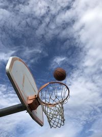 Low angle view of basketball hoop and ball against a blue sky