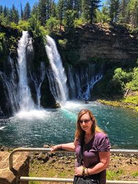 Full length of young woman against waterfall