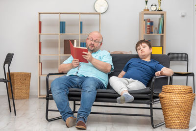 Friends using laptop while sitting on sofa at home