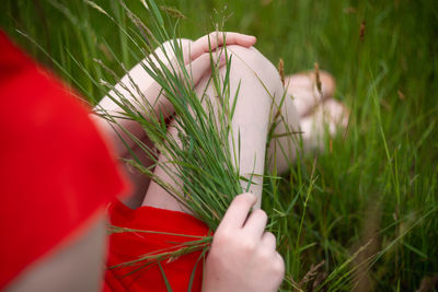 Low section of woman sitting on grassy land