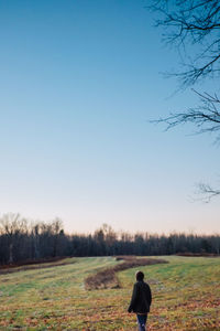 Rear view of woman standing on field against clear blue sky