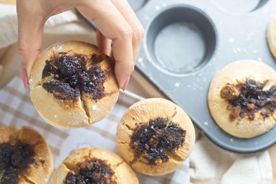 Cropped hand of woman picking muffins from tin 