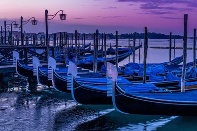 Boats moored in sea at sunset