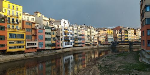 Buildings by river against sky in city